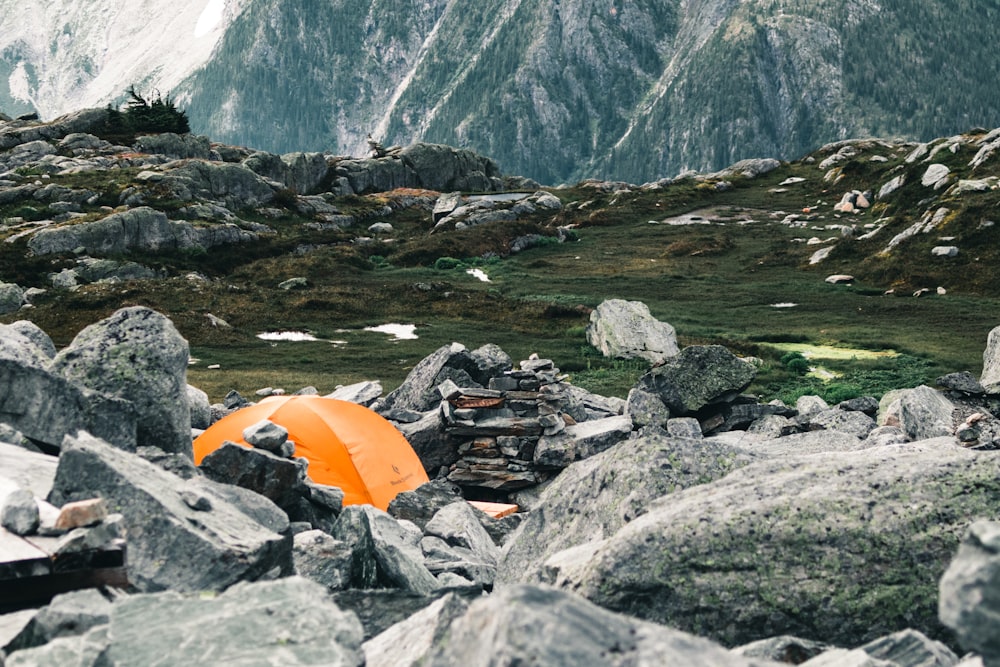 an orange tent sitting on top of a pile of rocks