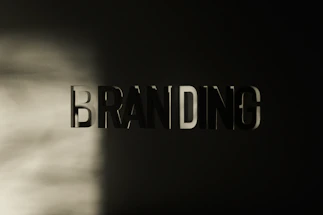 The word 'BRANDING' appears in large, bold, three-dimensional letters against a dark background, with a soft light casting shadows across the left side.