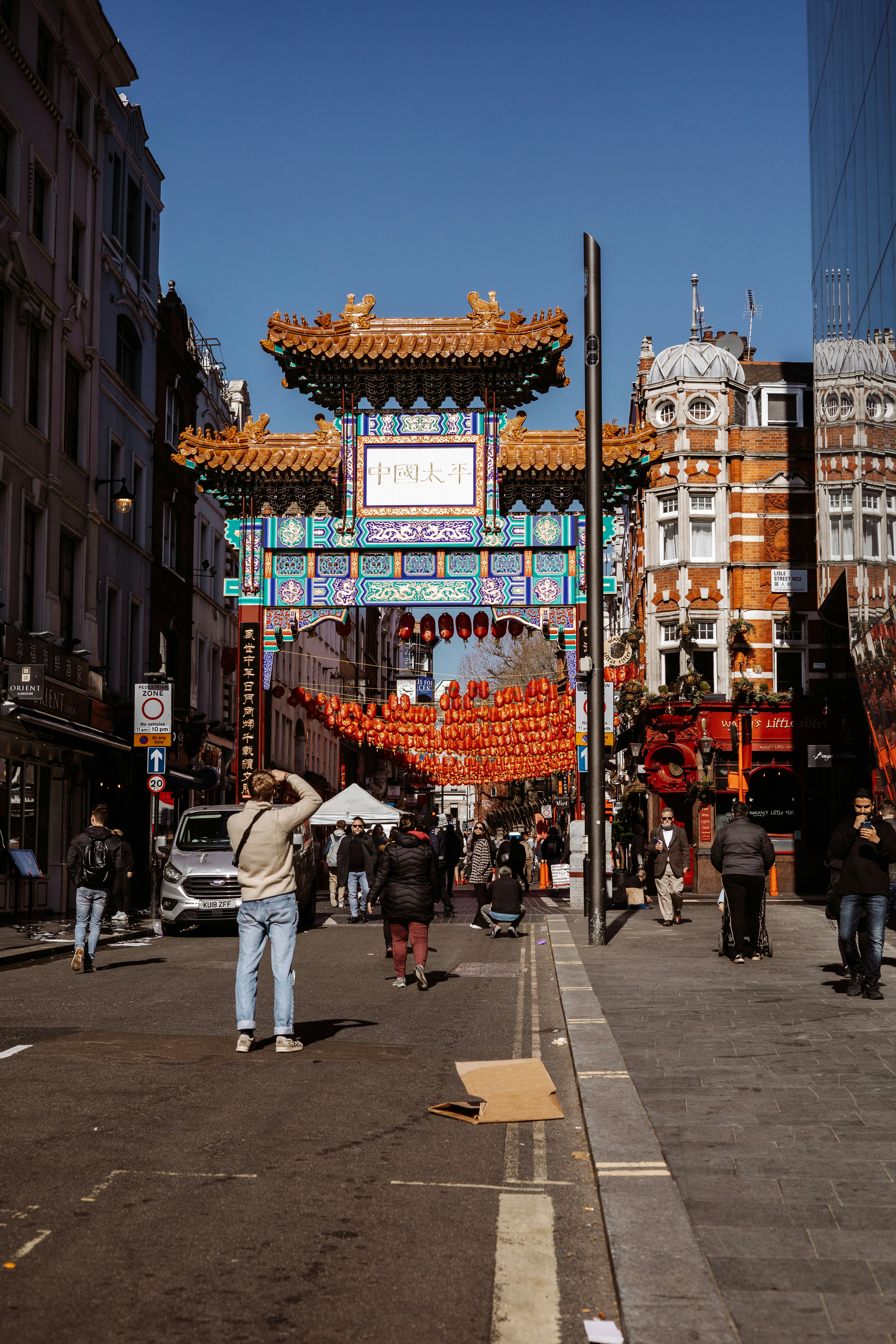 a group of people walking down a street next to tall buildings