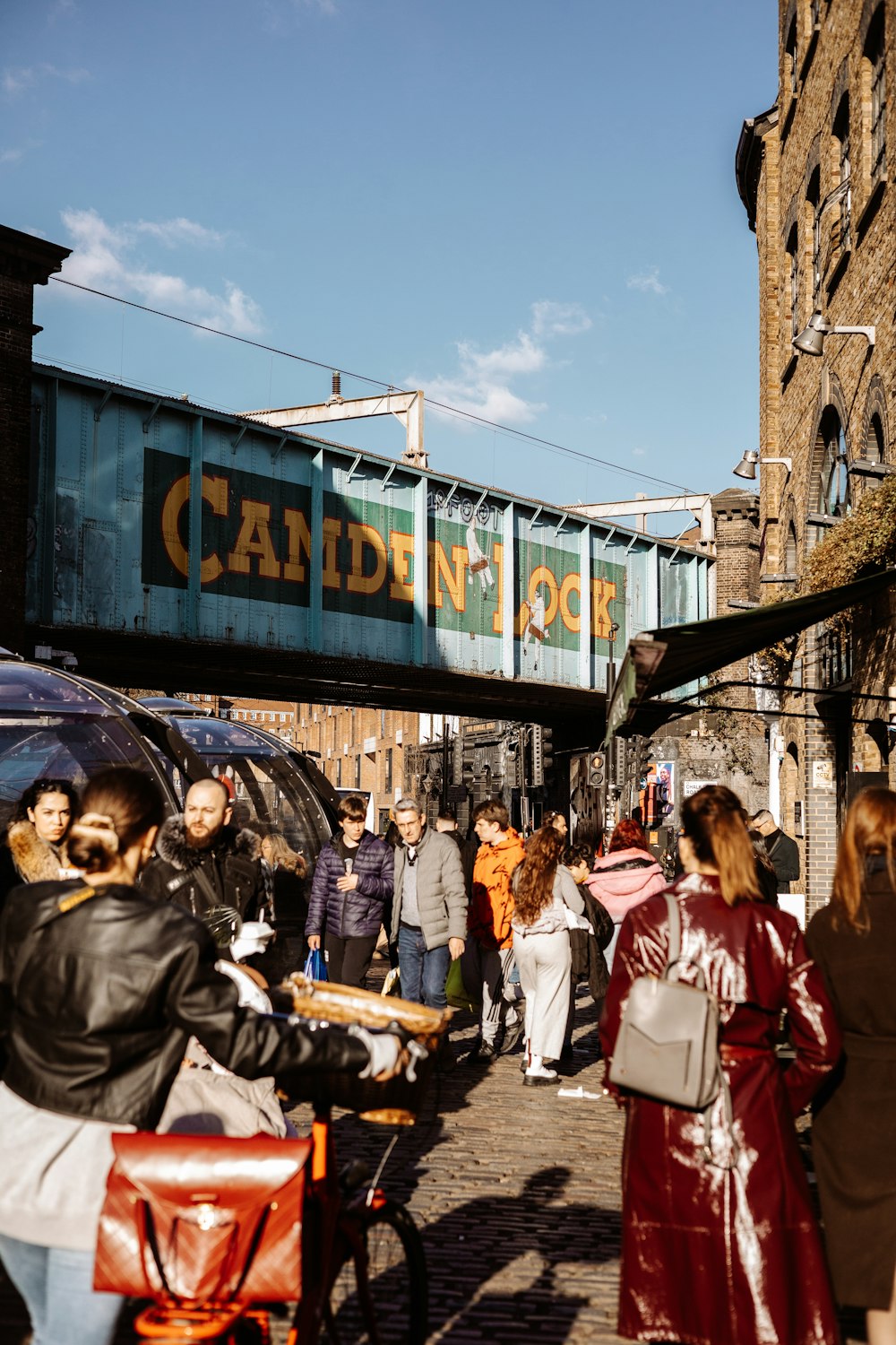 a group of people walking down a street next to a bridge