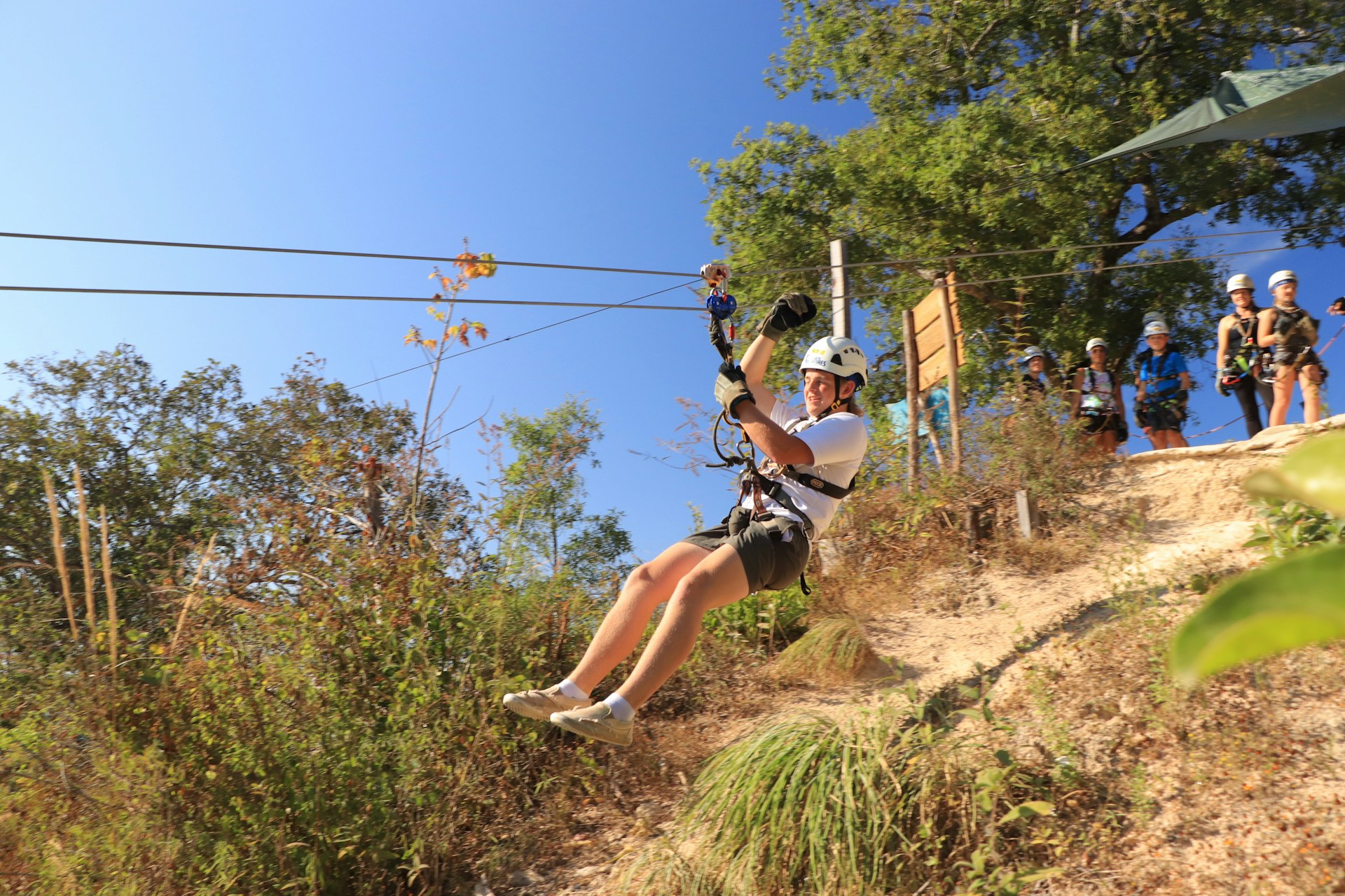 a man riding a zip line on top of a lush green hillside