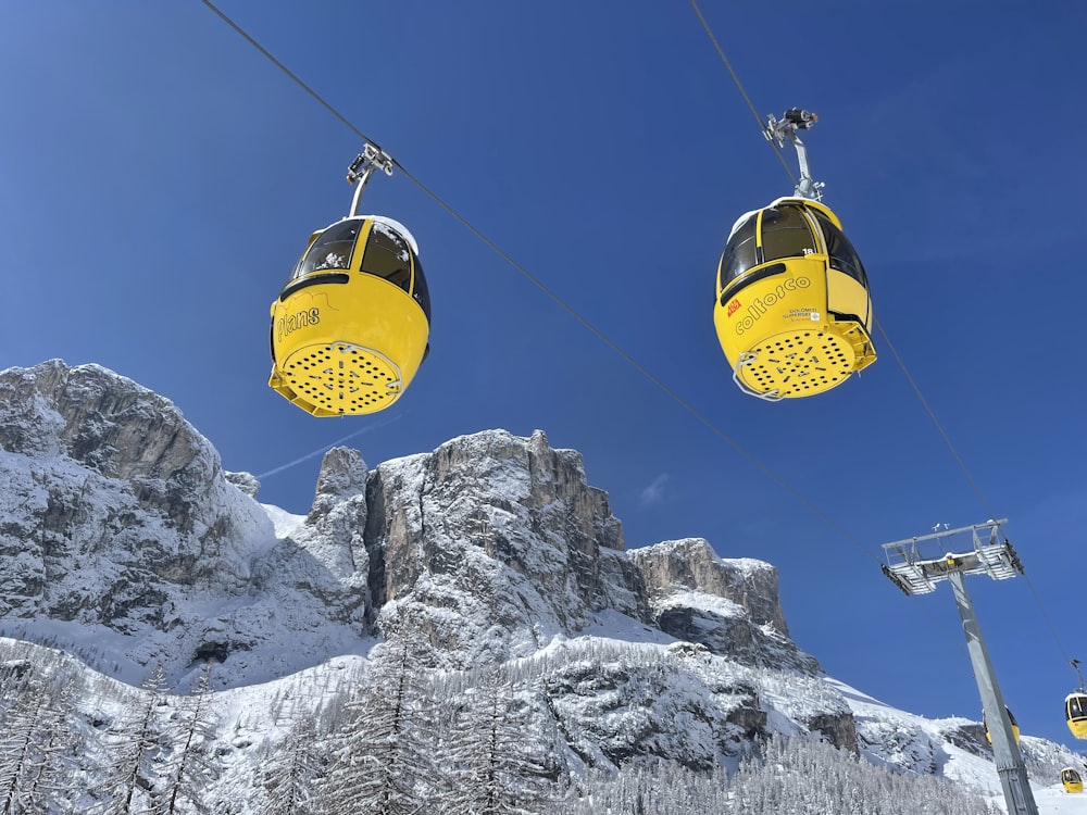 two yellow ski lifts above a snowy mountain