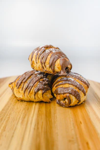 three pastries sitting on top of a wooden cutting board