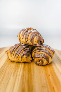 three pastries sitting on top of a wooden cutting board