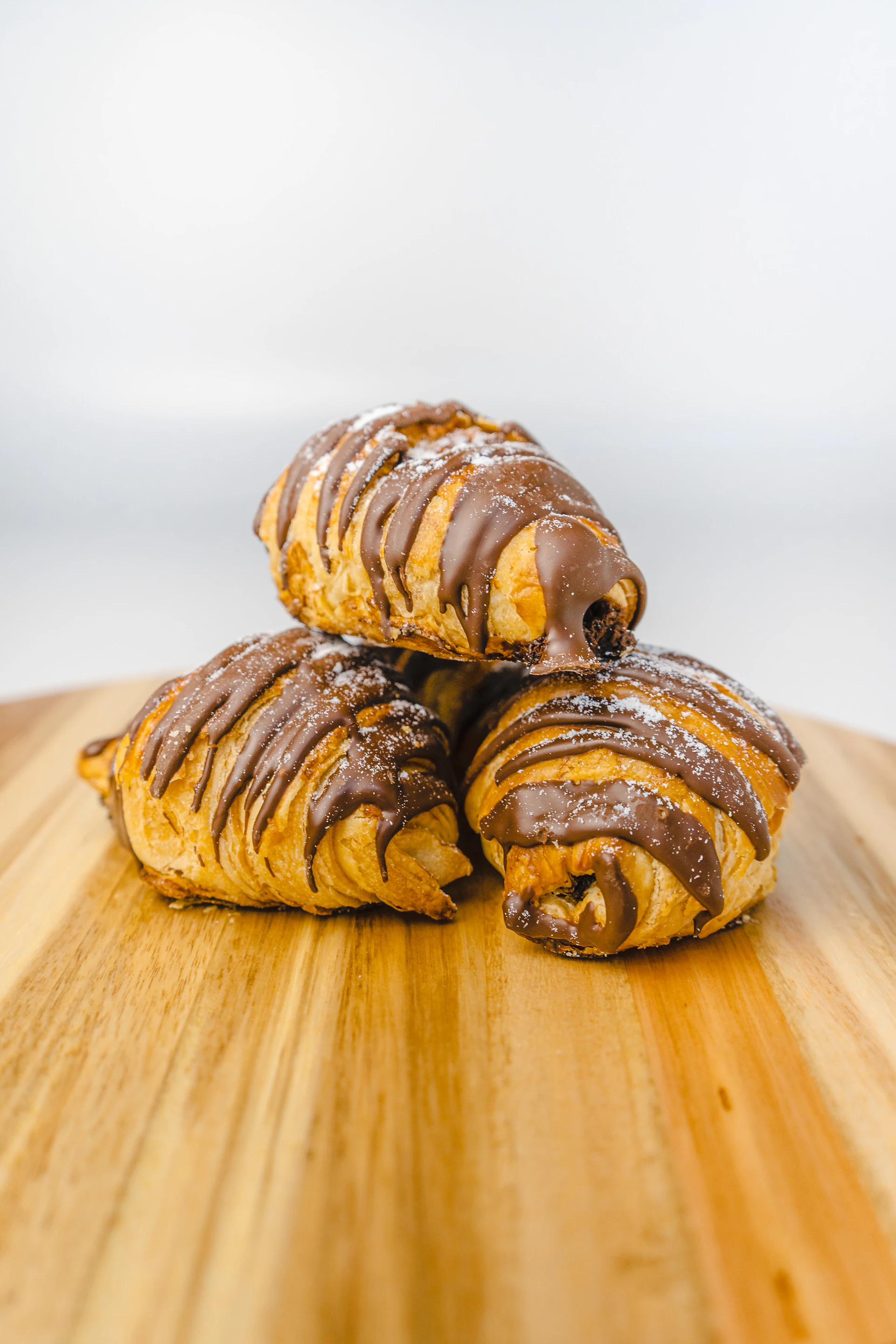 three pastries sitting on top of a wooden cutting board