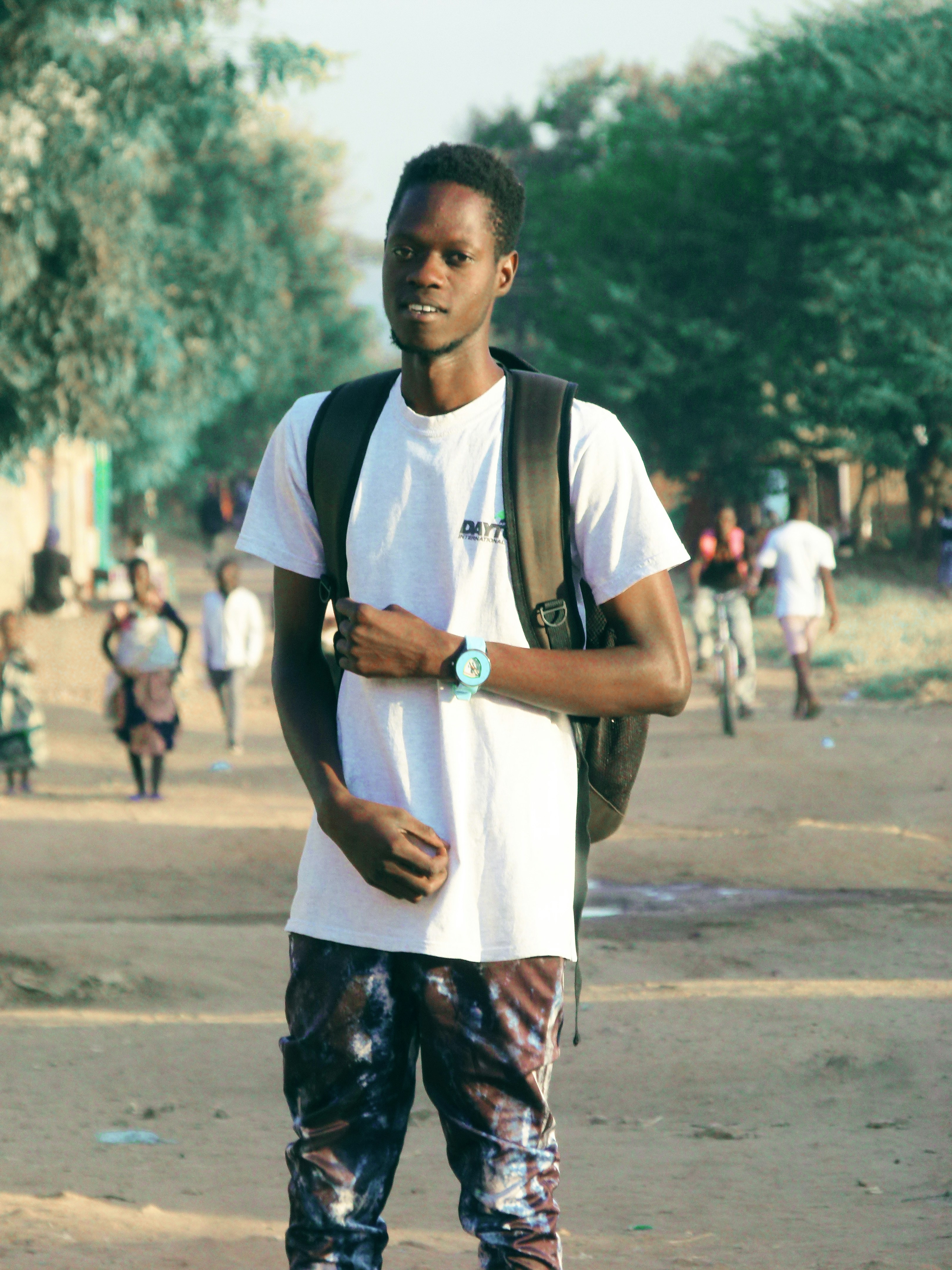 a man with a backpack standing on a dirt road