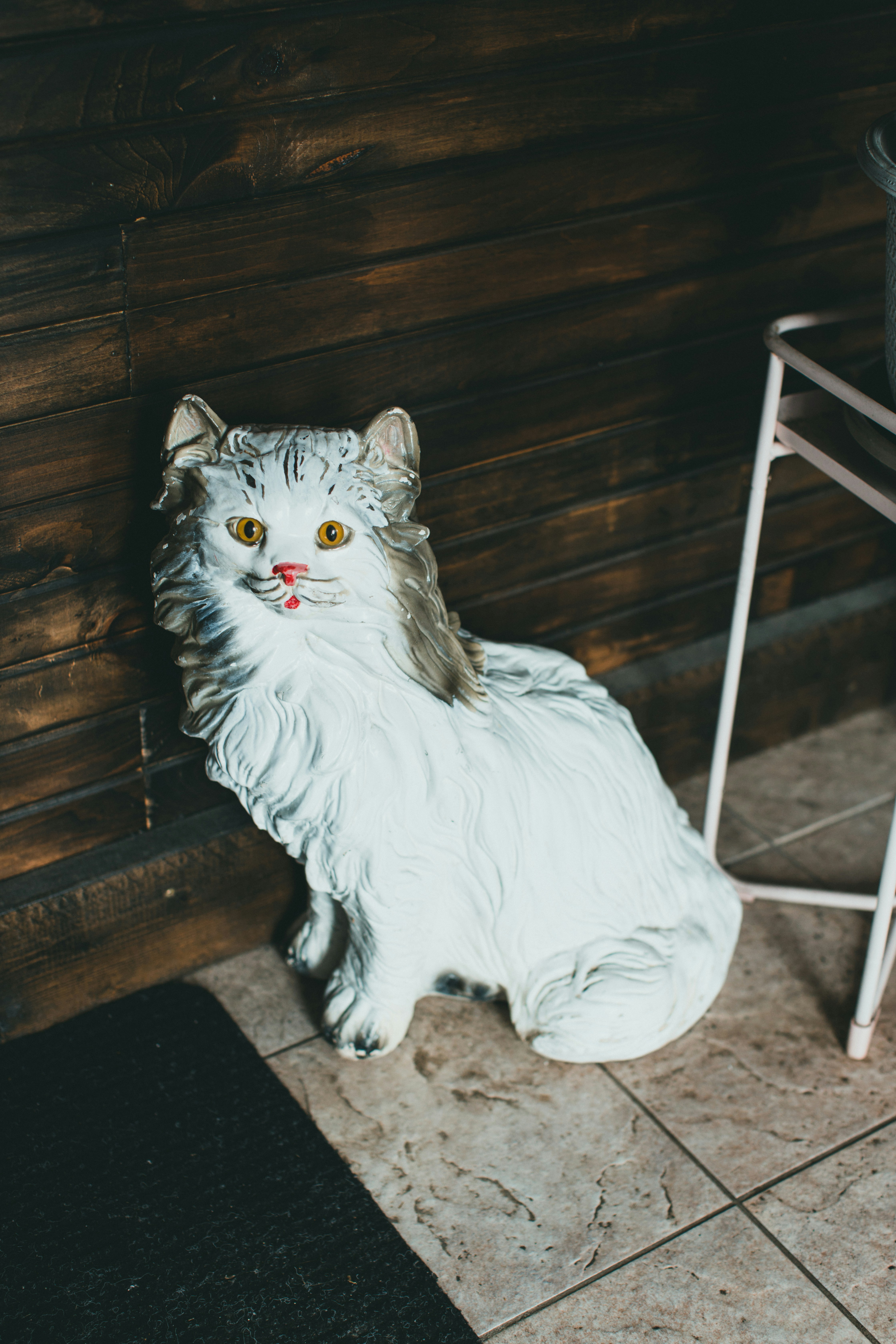a white cat statue sitting next to a chair