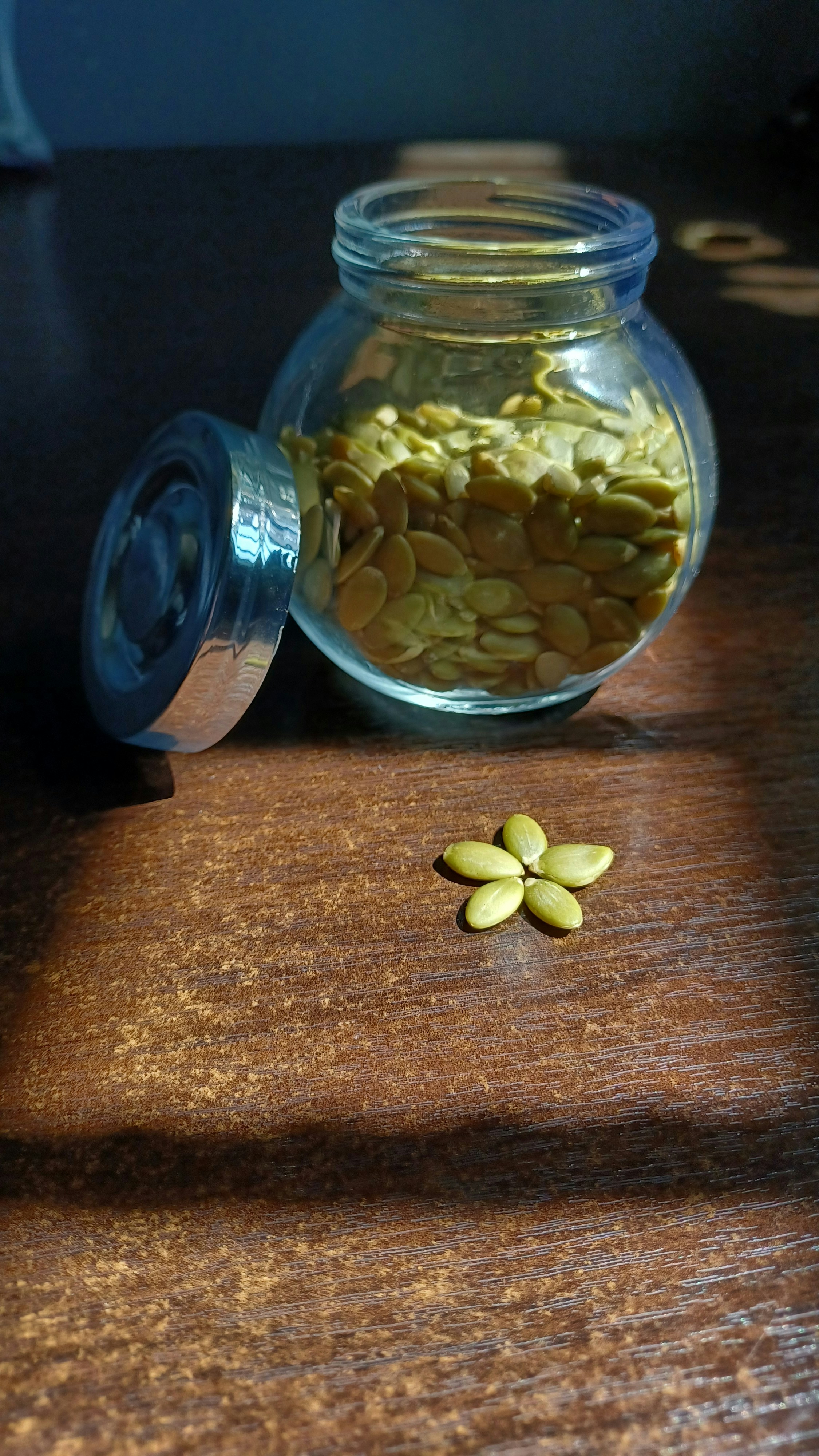 Green pumpkin seeds on a dark surface, natural light
