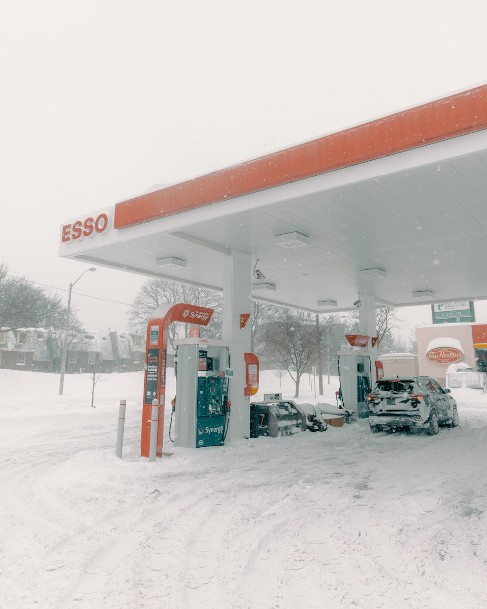 a couple of cars parked at a gas station in the snow