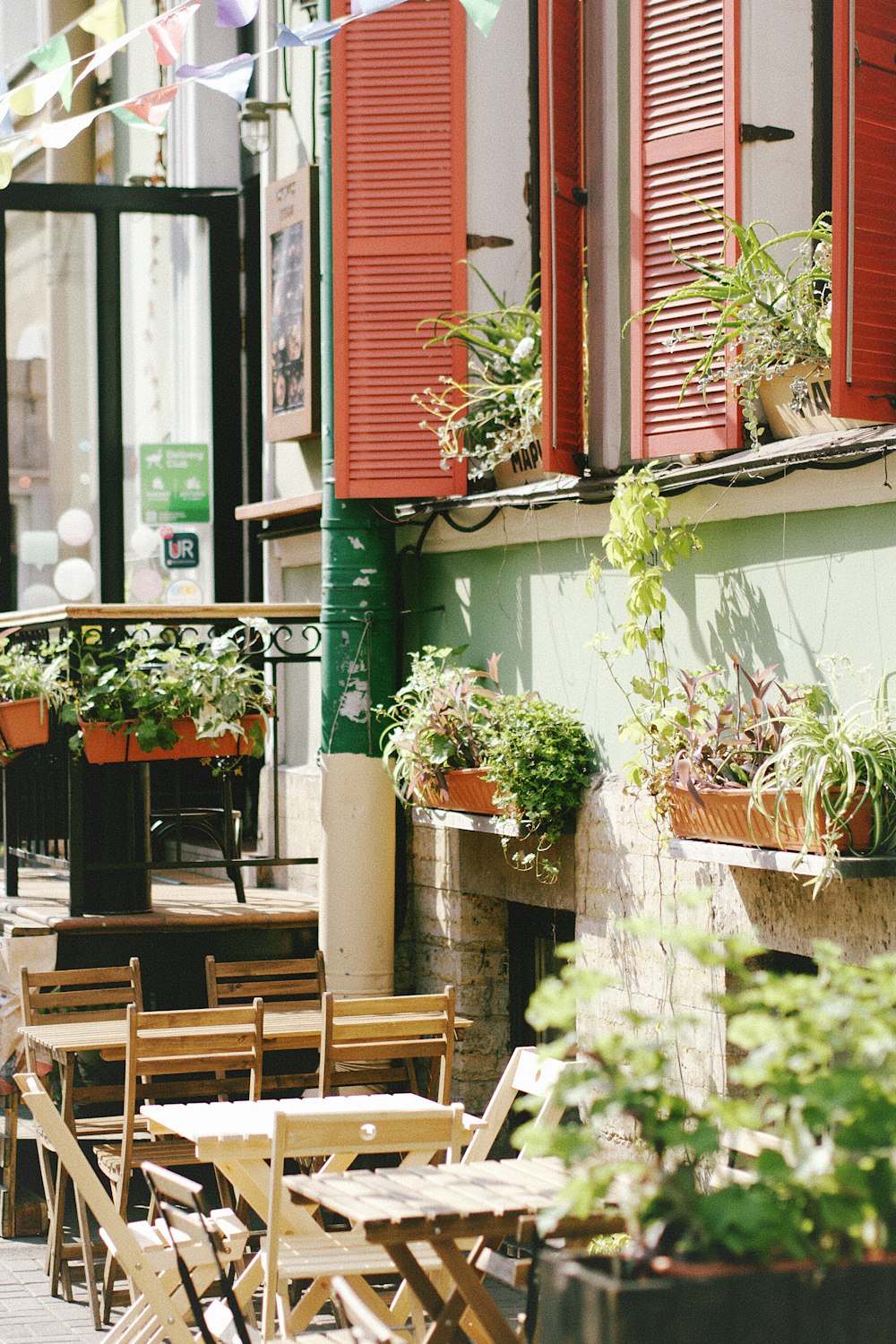 tables and chairs outside of a restaurant with red shutters