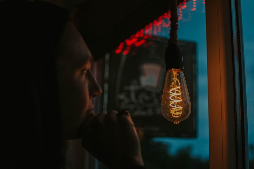 a person looking out a window at a light bulb