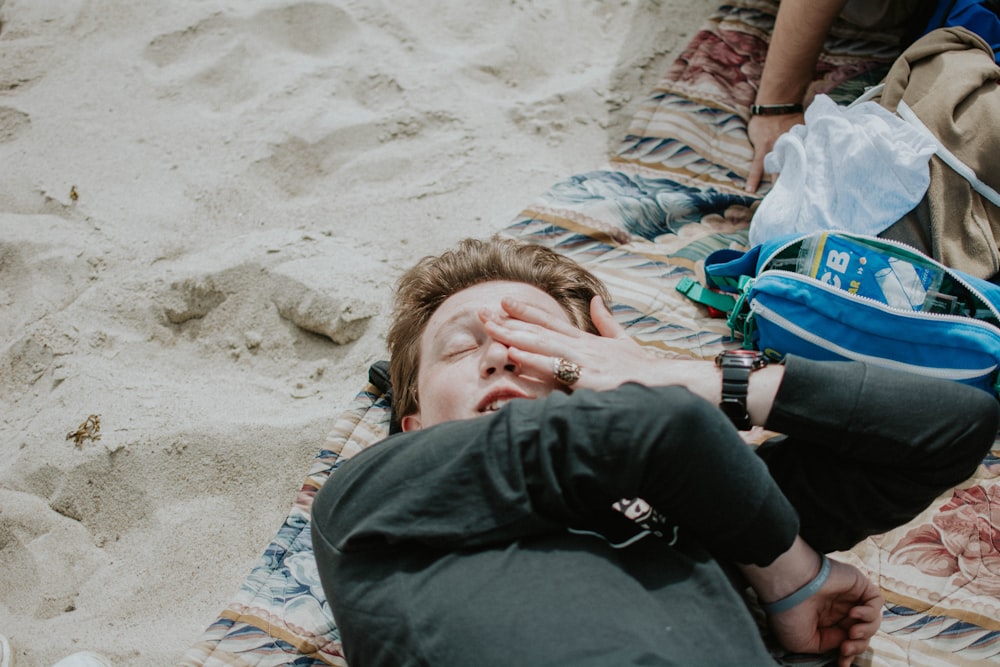 a person laying on a blanket on the beach