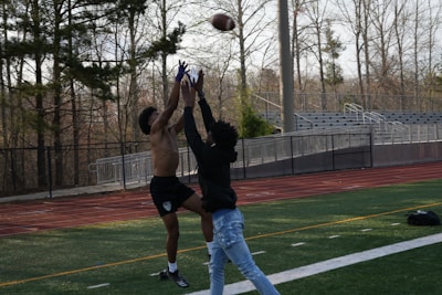 A dramatic touchdown catch in the end zone with players reaching out.