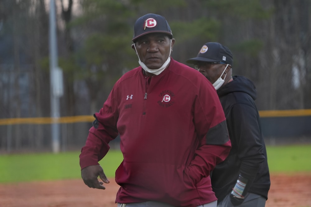 a man standing next to another man on a baseball field