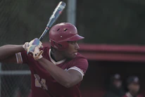 Close-up of a young player proudly holding a baseball bat ready to swing.