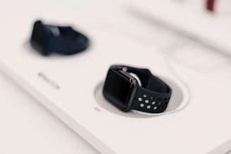 Close-up of two smartwatches displaying different apps, set against a high-tech workspace.