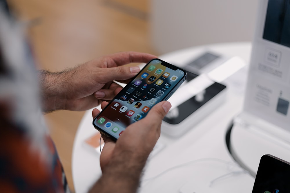 a man holding a cell phone in front of a computer