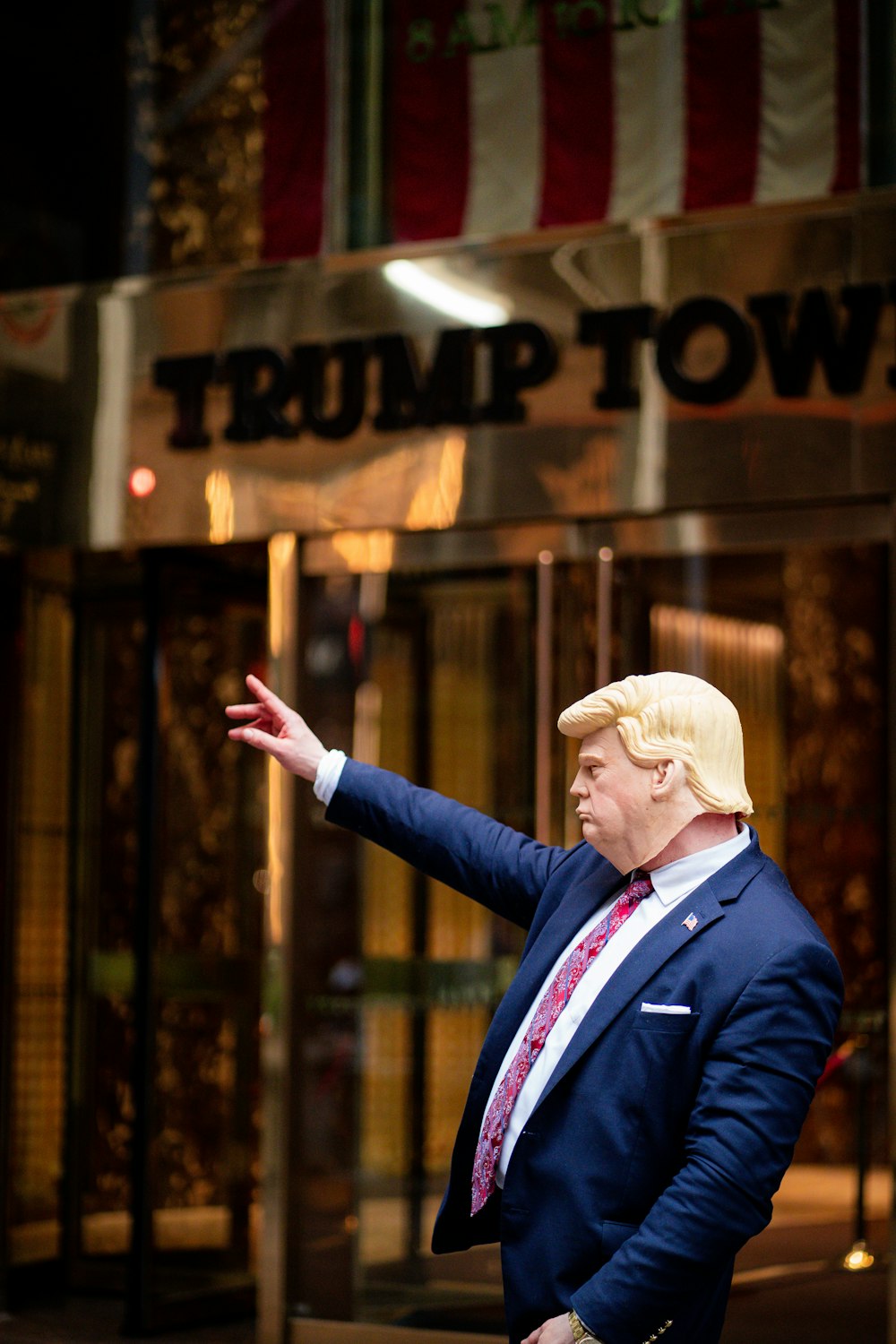 a man in a suit and tie standing in front of a trump building