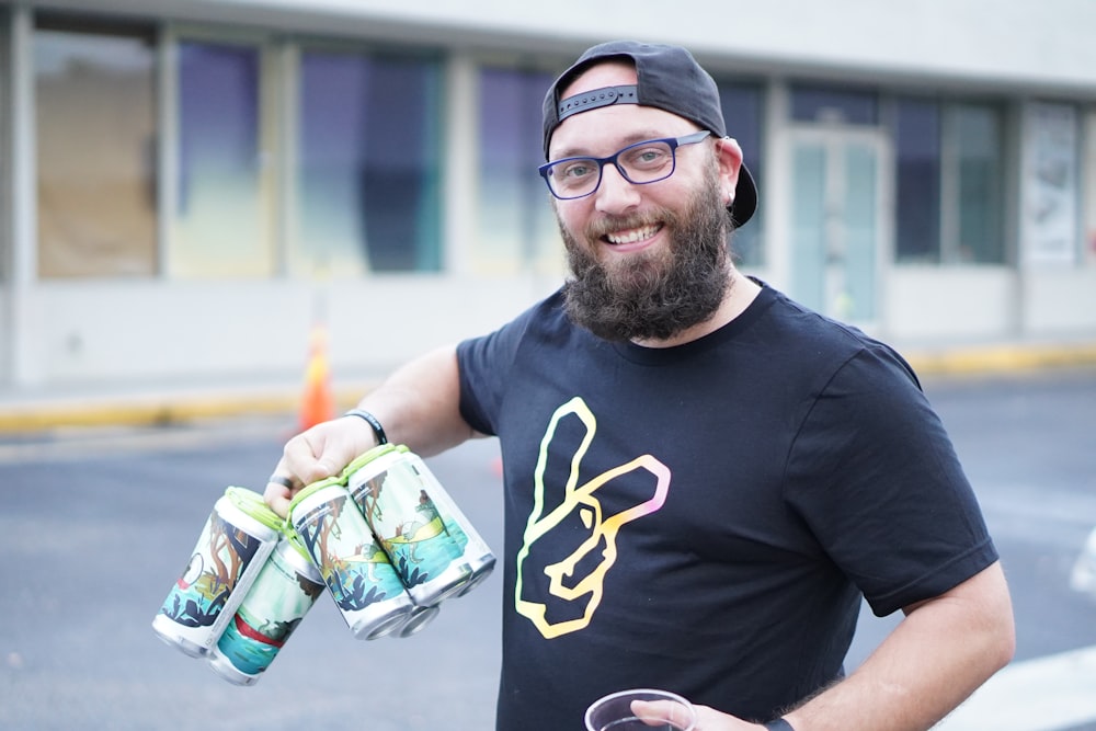 a man holding two cans of beer and a glass