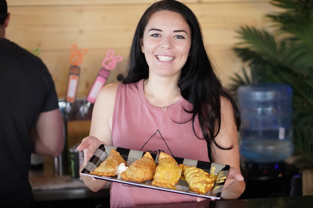 a woman holding a tray of pastries in front of a man