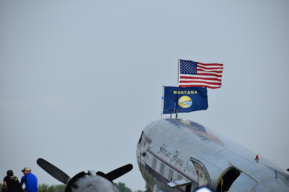 a silver airplane with a flag on top of it