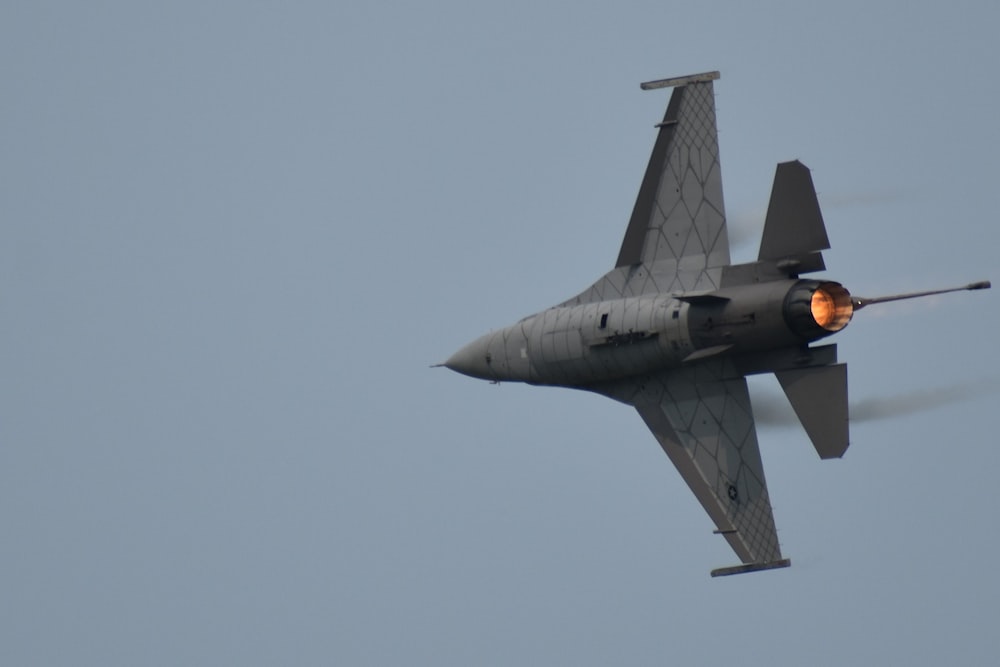 a fighter jet flying through a blue sky