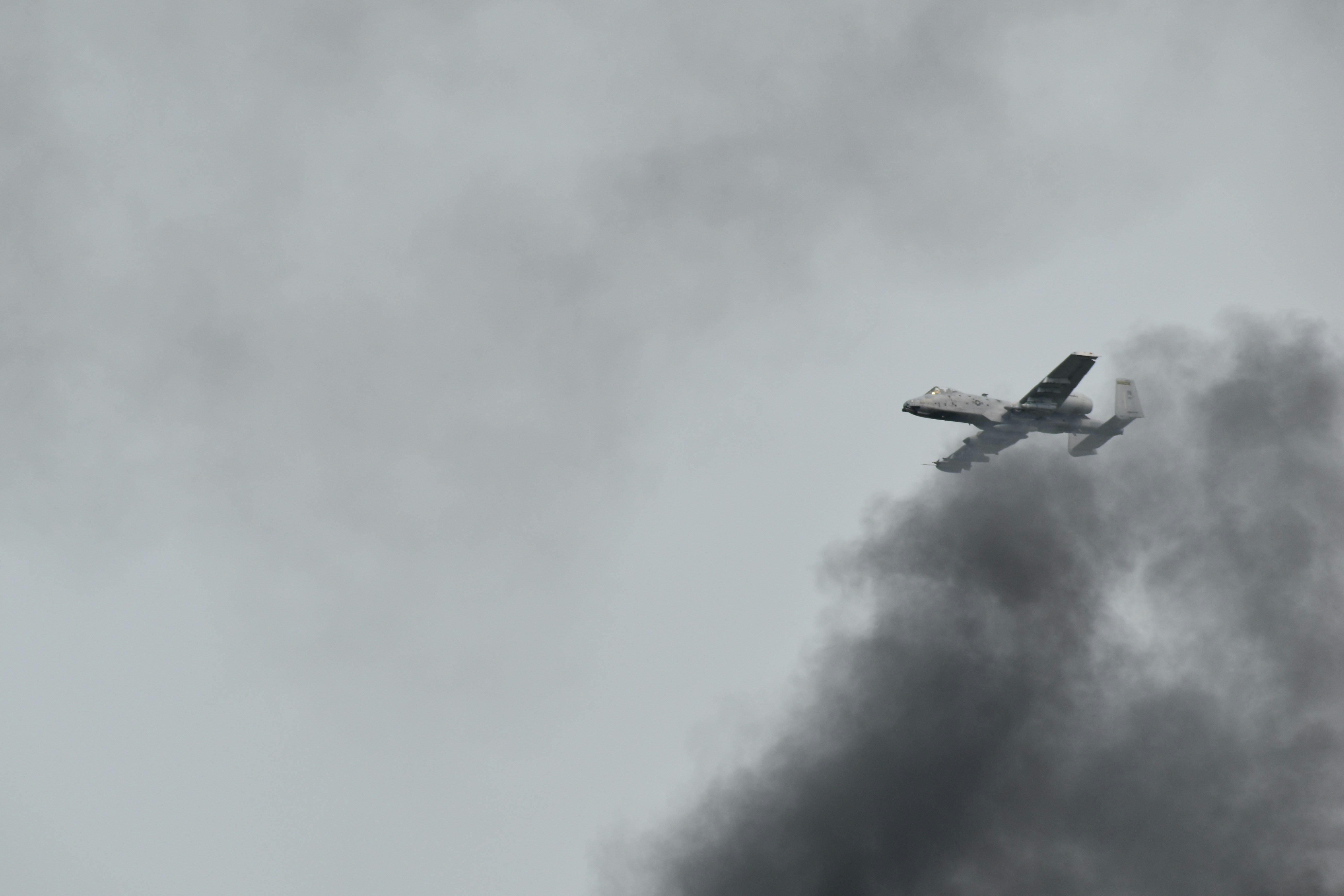 a plane flying in the sky with a lot of smoke coming out of it