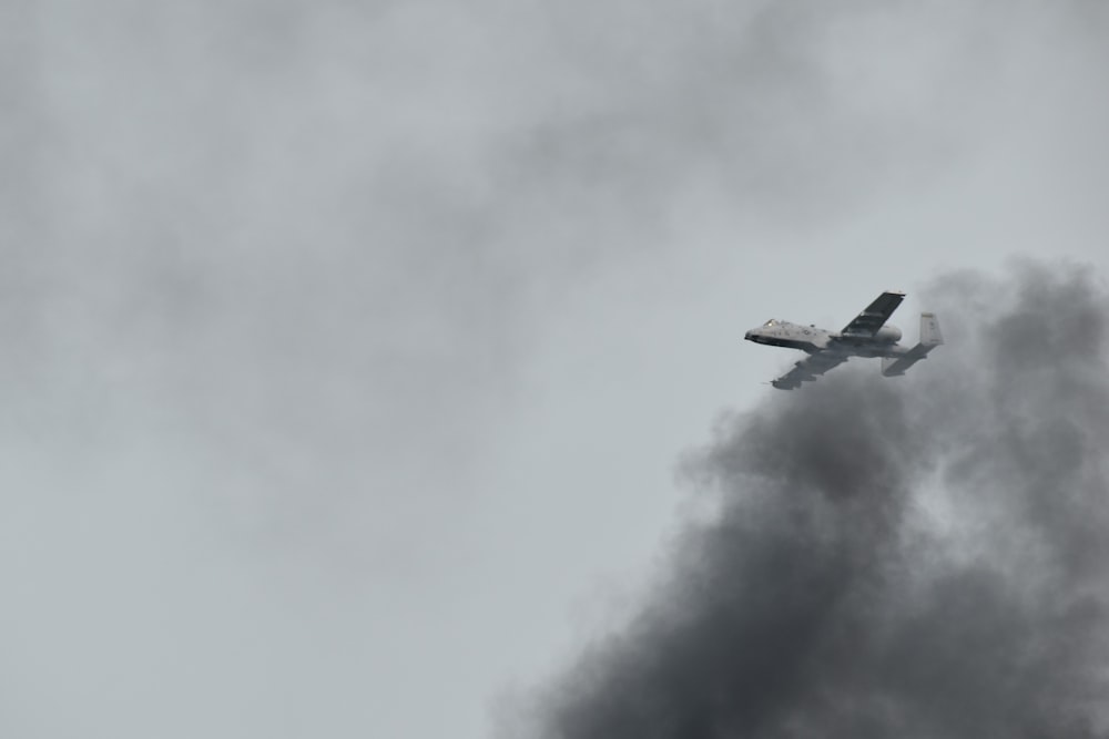 a plane flying in the sky with a lot of smoke coming out of it