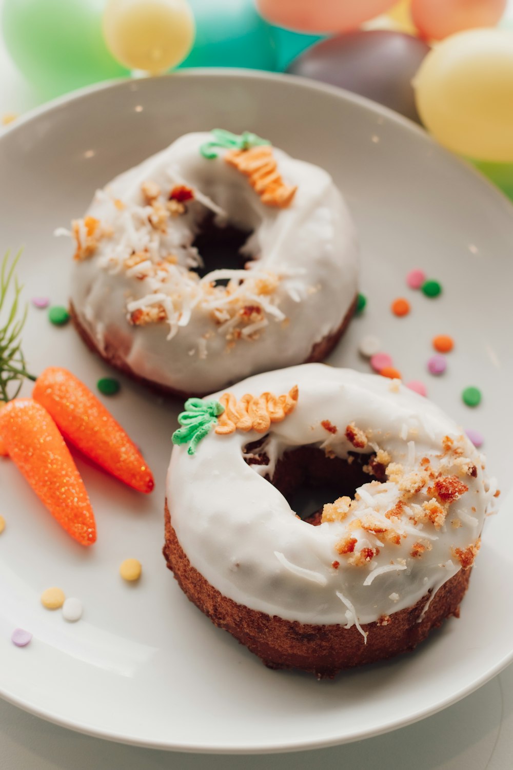 two glazed donuts with icing and sprinkles on a plate