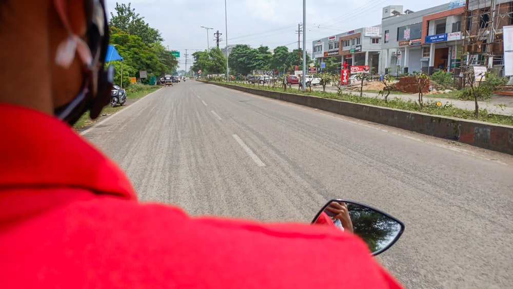 赤いジャケットを着た男が赤い車を通りを運転している