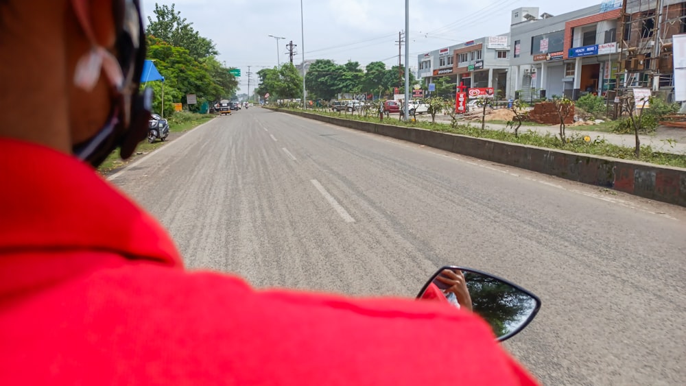 a man in a red jacket driving a red car down a street