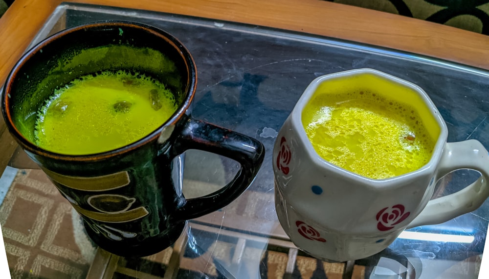 a couple of mugs filled with yellow liquid