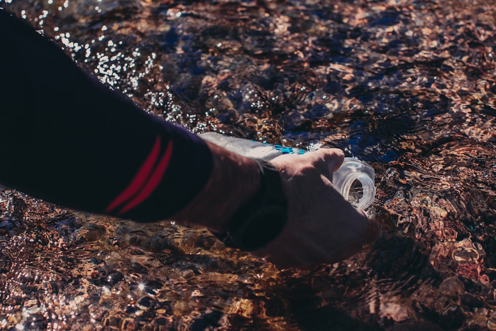 a person is holding a water bottle in the water