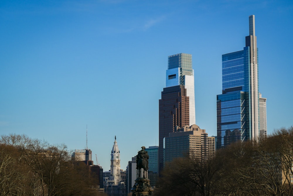 a city skyline with tall buildings and a statue