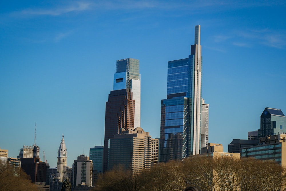 a city skyline with skyscrapers and trees in the foreground