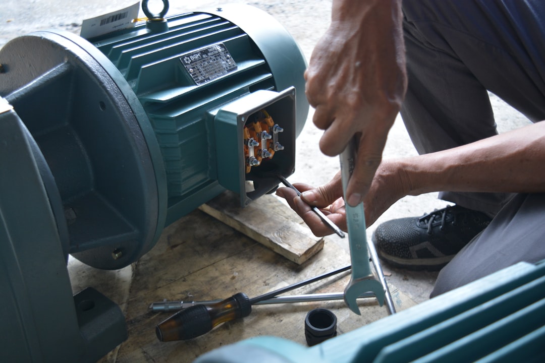 a man working on a machine with a wrench, A man testing the electric motor