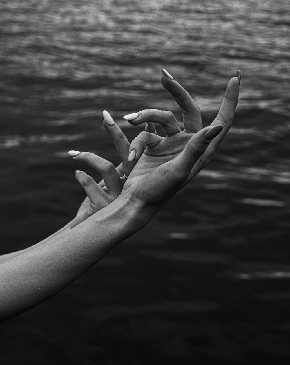 a black and white photo of two hands reaching towards each other