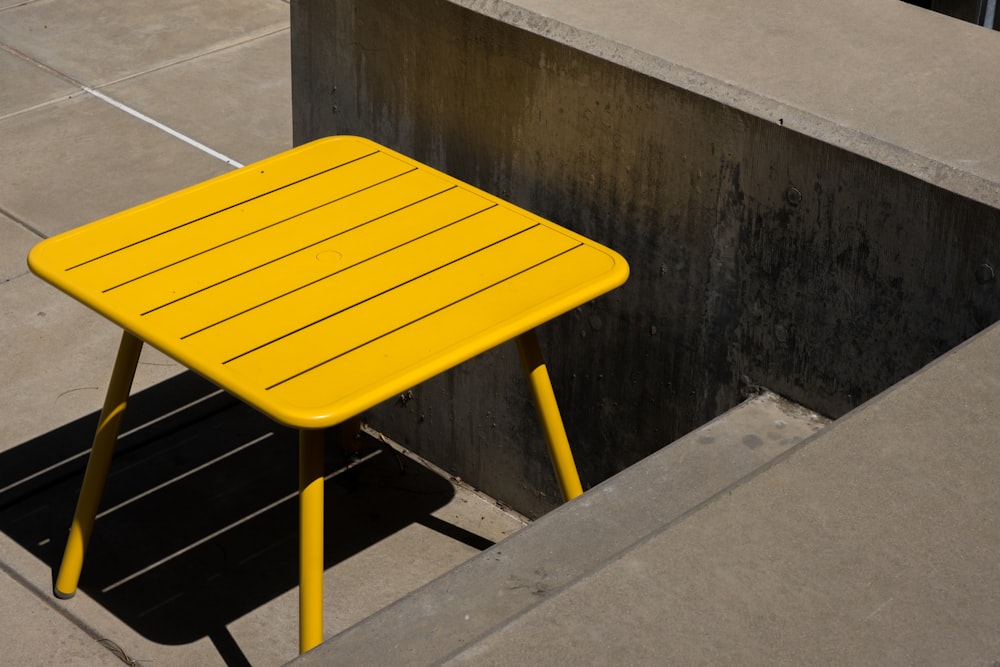 a yellow table sitting next to a cement wall