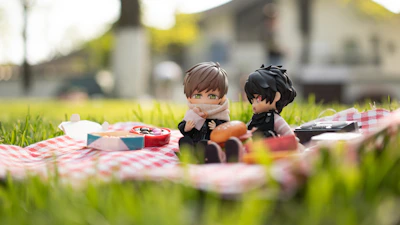 Two robots sharing a picnic blanket under a tree, with sandwiches and a vintage radio.