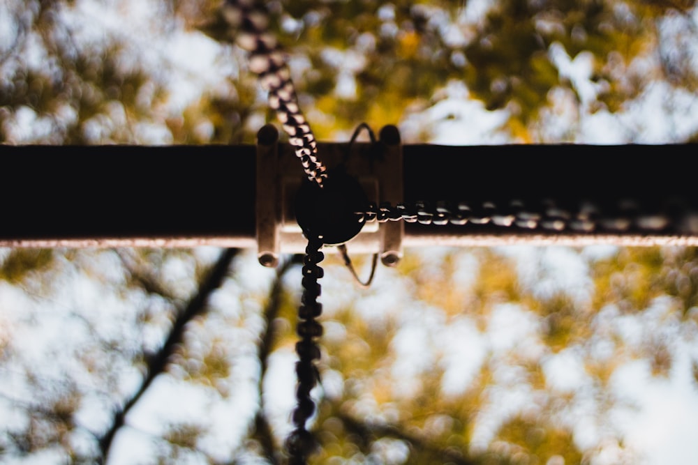 a close up of a chain link with trees in the background