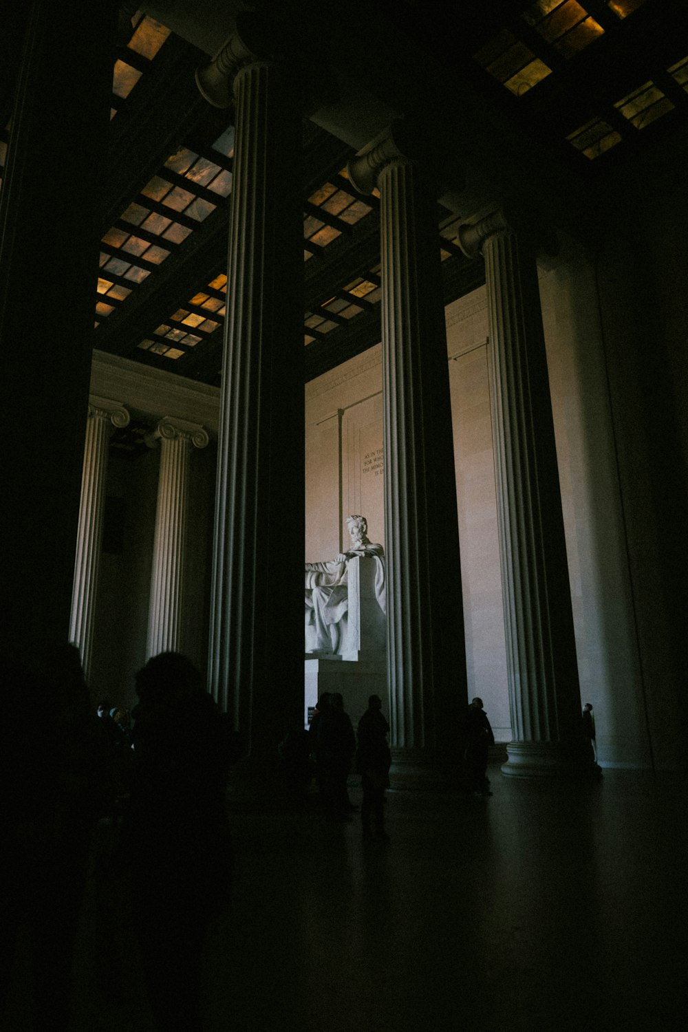 a group of people standing in a room with columns