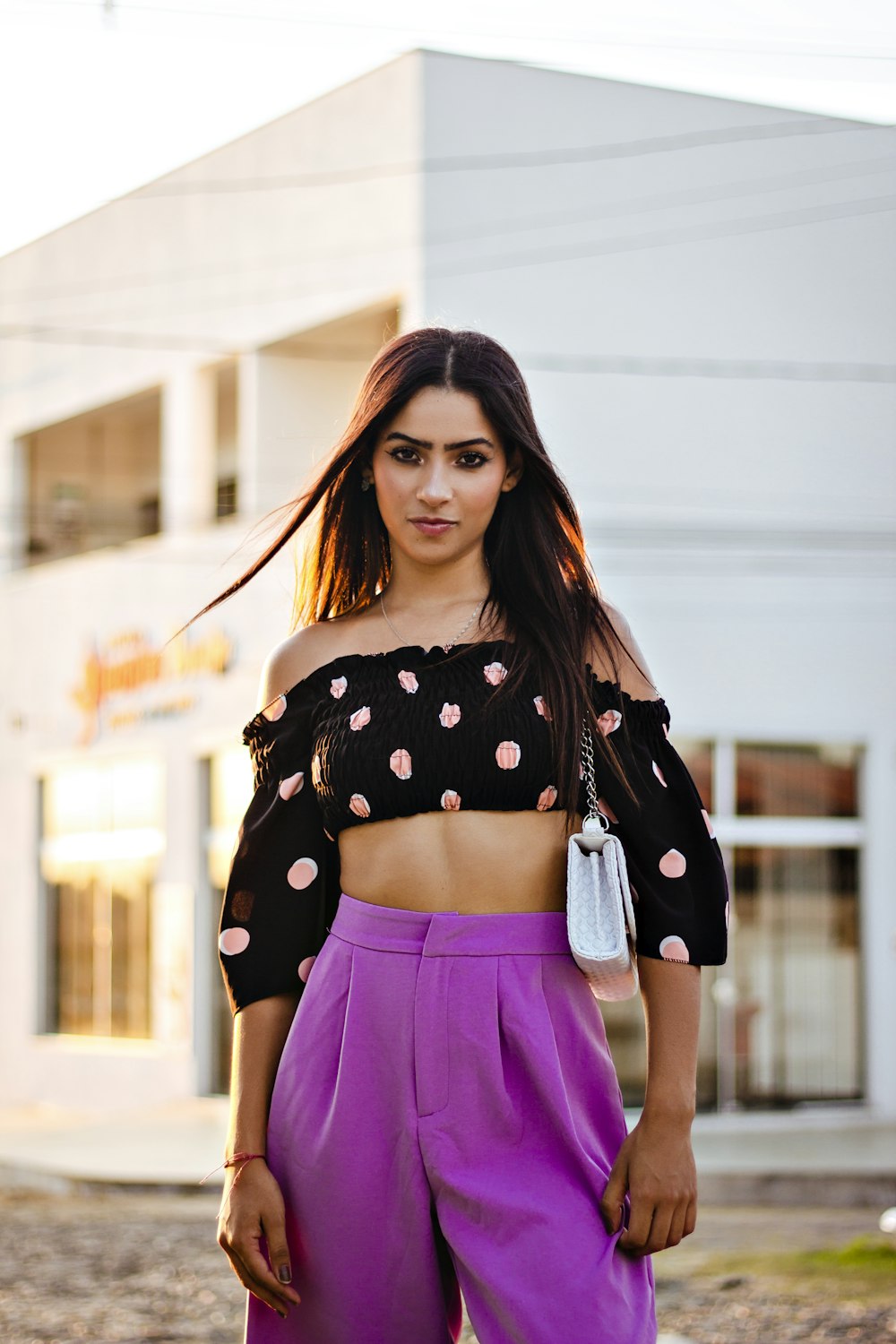 a woman in a crop top and purple pants
