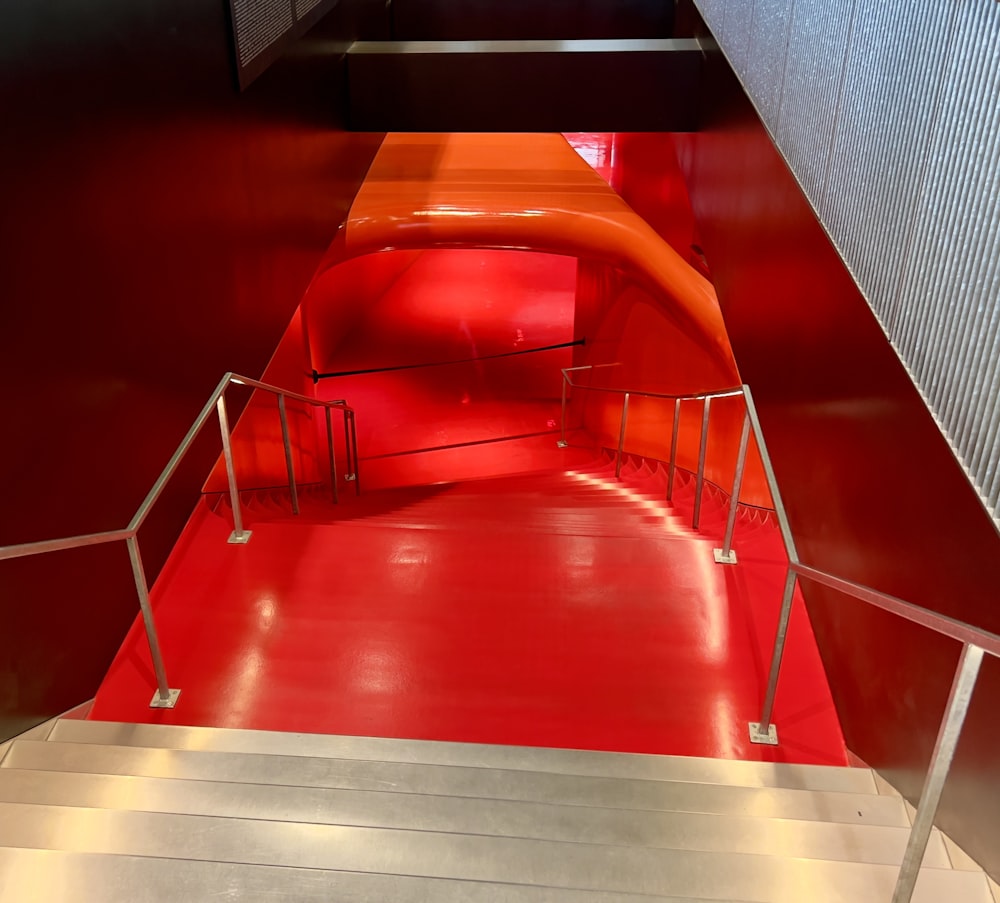 a red staircase with a red carpet and railing