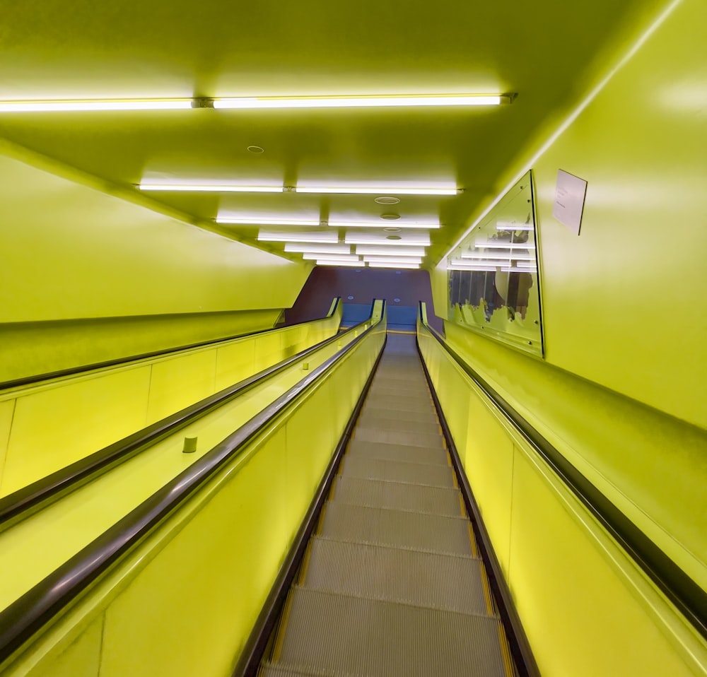 an escalator in a building with yellow walls