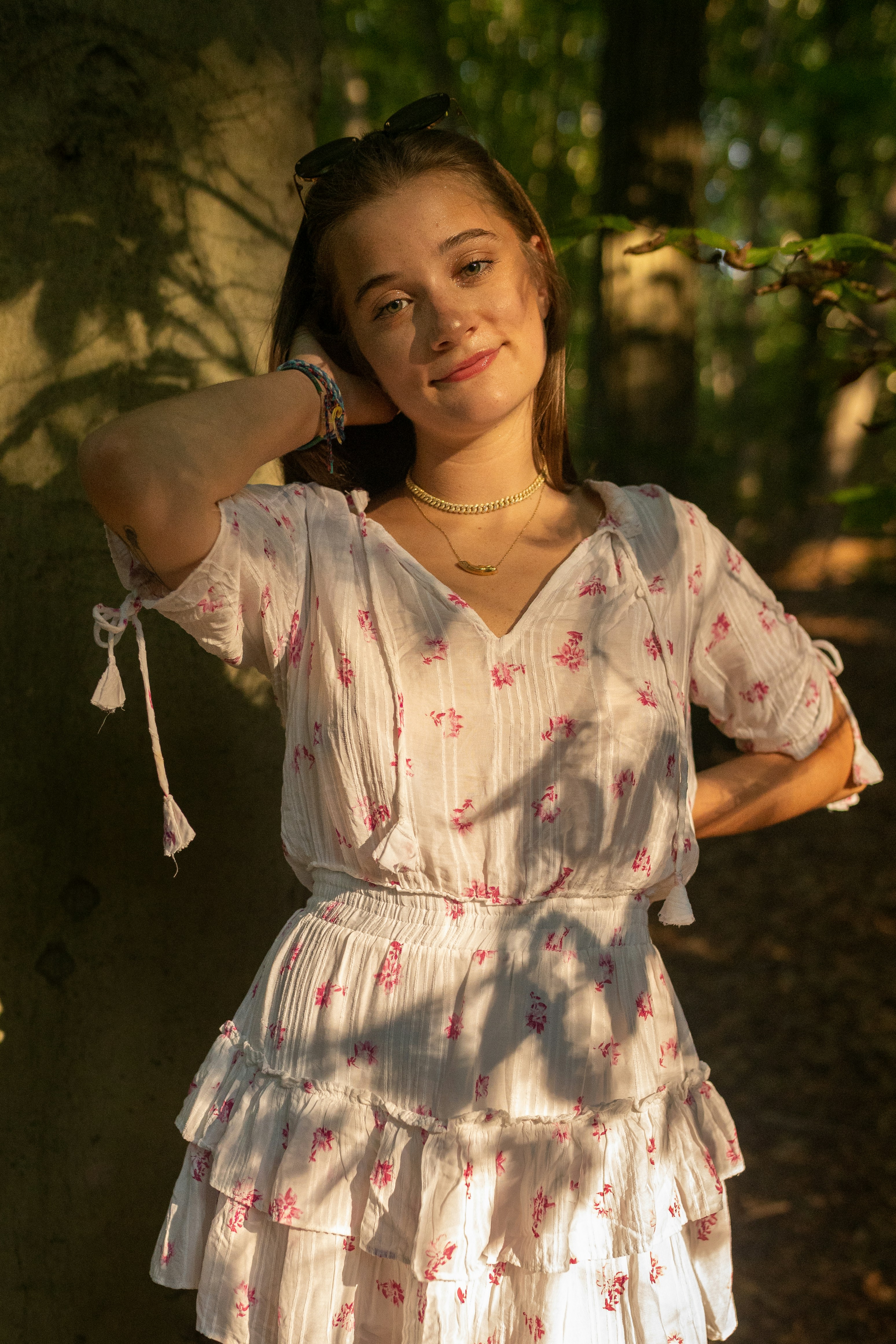 a woman standing next to a tree wearing a white dress
