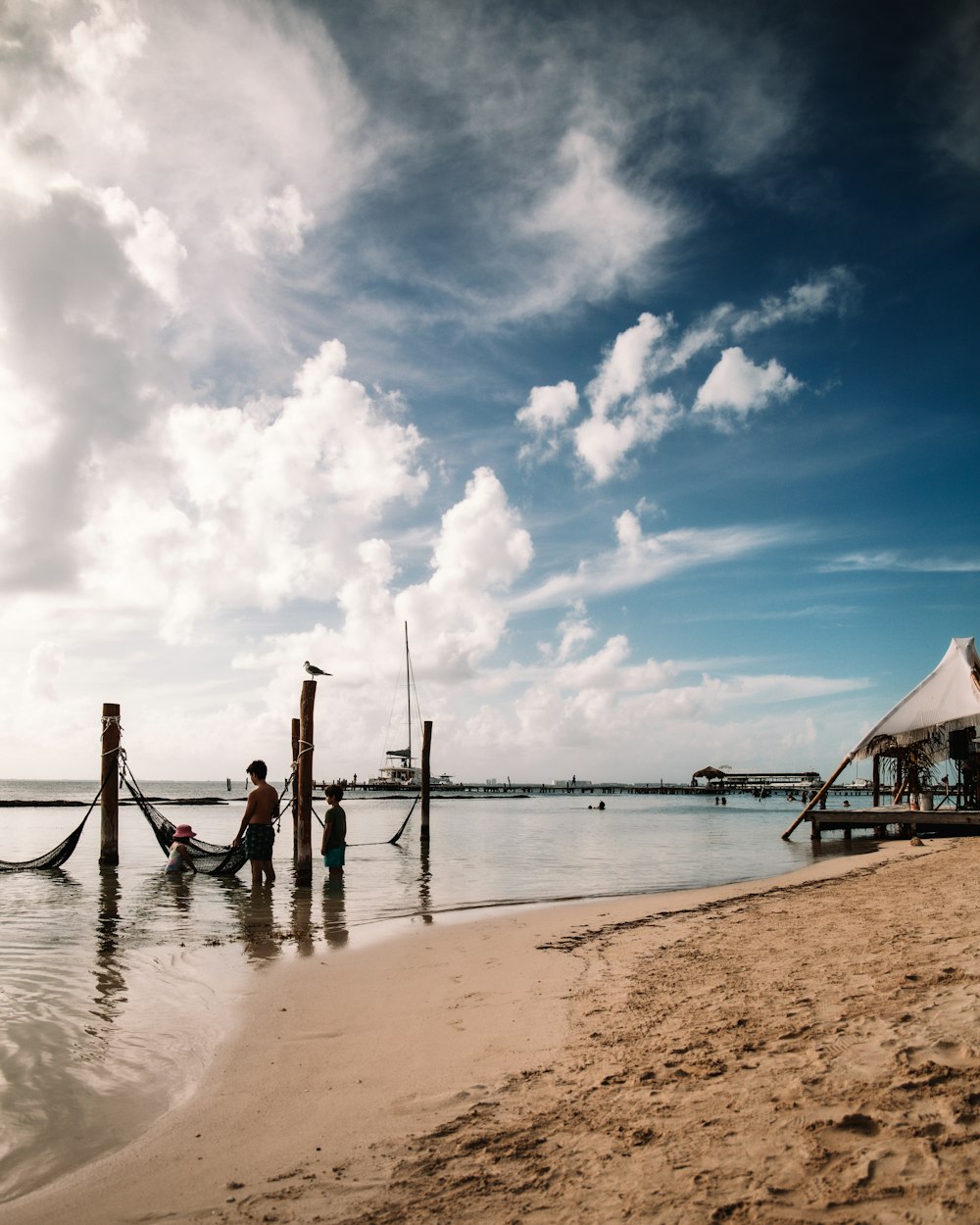 a couple of people standing on top of a sandy beach