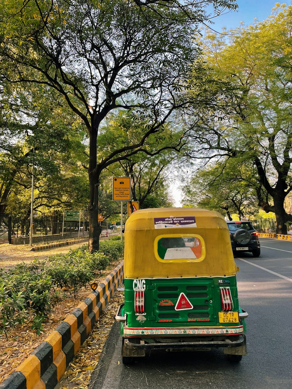 a green and yellow vehicle driving down a street