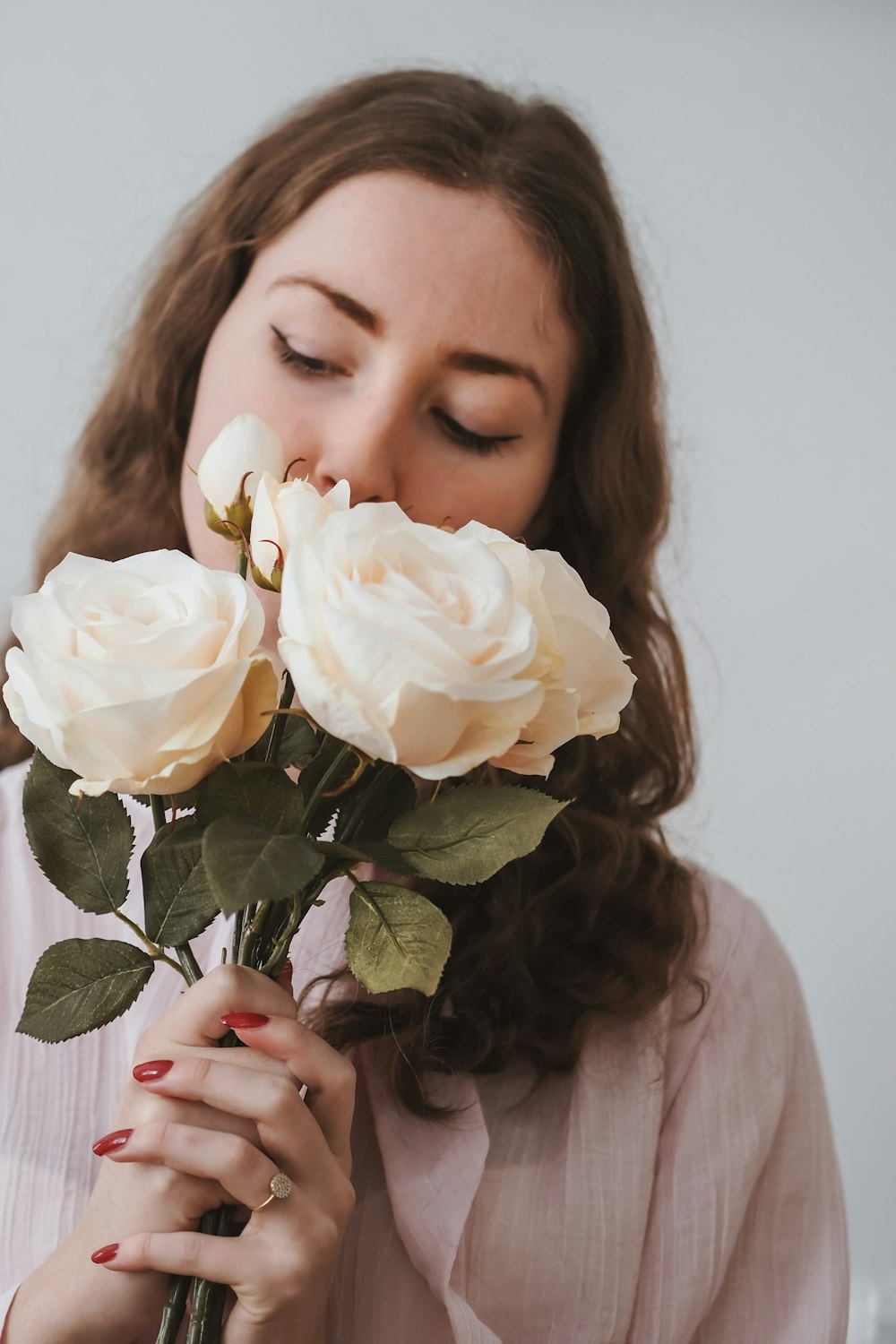 a woman smelling a bunch of white roses