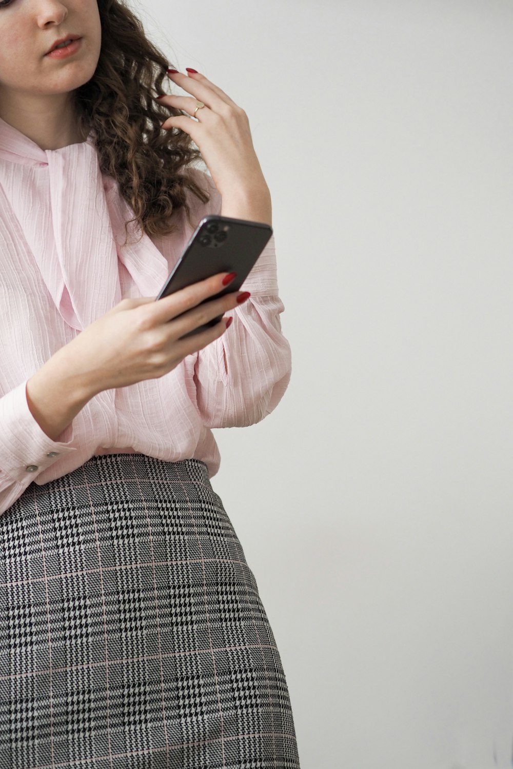 a woman in a pink shirt is holding a cell phone