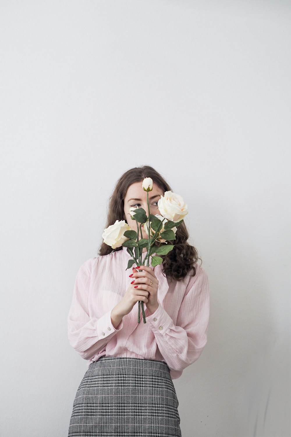 a woman holding a rose up to her face